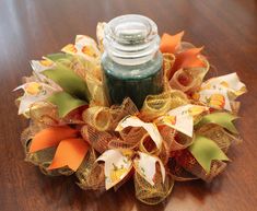 a glass jar sitting on top of a wooden table covered in burlocks and ribbons