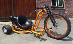 an orange and black motorized tricycle parked in front of a brick building