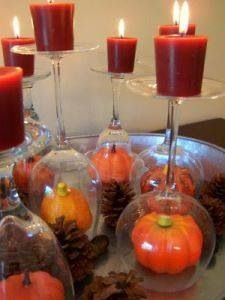 there are many candles in glass vases with pumpkins and pine cones