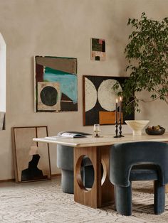 a dining room table with two chairs and a potted plant