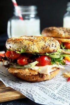 two sandwiches with lettuce, tomato and cheese on them next to a glass of milk