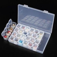 an open plastic box filled with lots of small items on top of a black surface