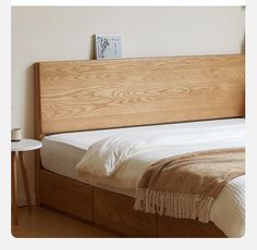 a bed with a wooden headboard and white linens on it, next to a night stand