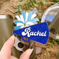 a person holding up a blue and white sticker with the word rachel on it