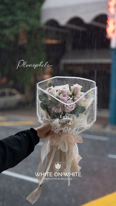 a person holding a clear box with flowers in it on the side of the road