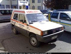 an ambulance is parked in the parking lot next to some other cars and trucks on the street