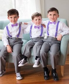 three young boys sitting on top of a blue couch wearing matching ties and suspenders