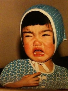 a young child wearing a blue and white dress with a hood on it's head