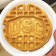 a waffle with the word ucsc on it is held up in a white plate