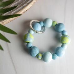 a close up of a bracelet on a table with a plant in the back ground