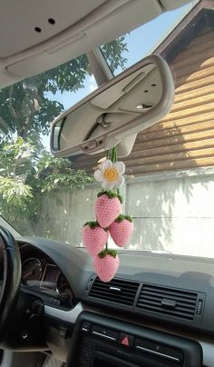 the interior of a car is decorated with pink strawberries and flowers hanging from the dash board