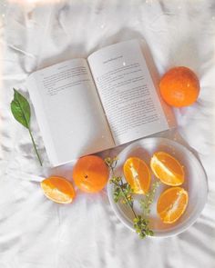 an open book and some oranges on a plate