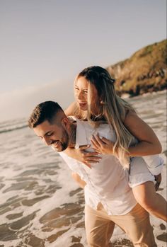 a man carrying a woman on his back at the beach