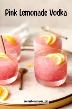 three pink lemonade vodkas on a marble platter with silverware and spoons