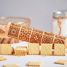 a wooden rolling pin with cut out cookies next to it