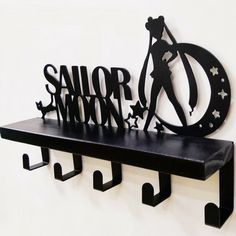 a metal sign that says sailor moon on top of a shelf next to two hooks