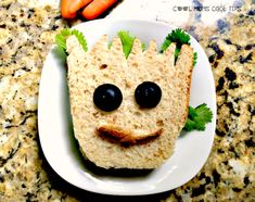 a sandwich made to look like a face with carrots on the side and eyes