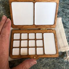 an open wooden box with white squares on the front and sides, held in someone's hand