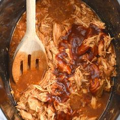 the meat is being cooked in the slow cooker with a wooden spoon and fork