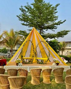 a yellow and white tent set up in the middle of a field with baskets around it