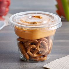 a plastic container filled with pretzels on top of a wooden table