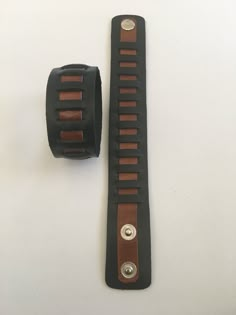 a black watch band with brown stitching and two metal studs on each side