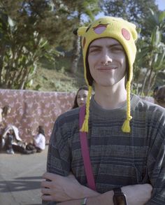 a young man wearing a yellow hat and holding his arms crossed in front of him