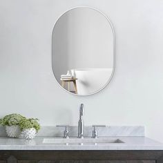 a bathroom sink with a mirror above it and a vase on the counter next to it