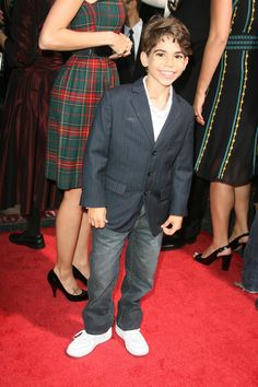 a young boy in a suit standing on a red carpet