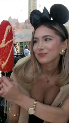 a woman holding up a mickey mouse lollipop