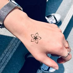 a woman's hand with a small flower tattoo on it