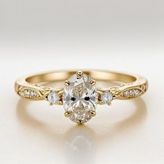 a yellow gold engagement ring with an oval cut diamond in the center and side stones