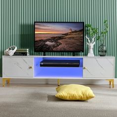 a flat screen tv sitting on top of a white entertainment center next to a yellow pillow