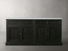 a black buffet with marble top and brass pulls on the bottom, in front of a gray wall