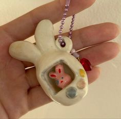 a hand holding a small ceramic rabbit with beads on it's back and a beaded necklace around its neck