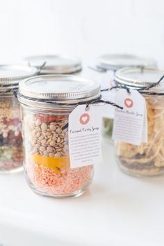 jars filled with different types of food on top of a white table next to each other