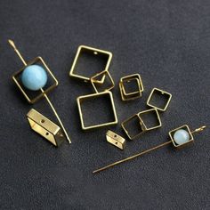 several pairs of earrings sitting on top of a black surface next to pins and needles