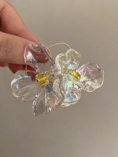 a hand holding a glass flower with yellow accents