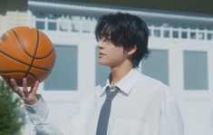 a young man holding a basketball in his right hand and wearing a shirt and tie