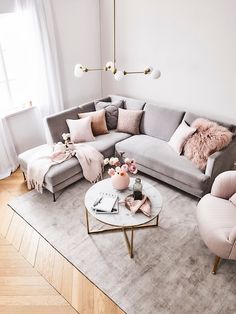 a living room with grey couches and pink pillows on the floor, along with other furniture