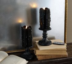 two candles are sitting on top of books next to an open book and cell phone