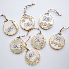 six embroidered ornament hanging from twine string on white table top with tags attached