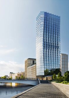 a very tall building sitting next to a body of water in front of a bridge