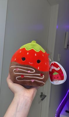 a hand holding up a stuffed strawberry with chocolate frosting and sprinkles