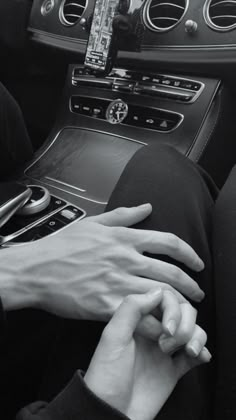 two hands on the steering wheel of a car, one holding the other's hand