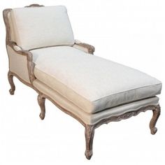 an antique chaise lounge chair with white linen upholstered seat and back cushions