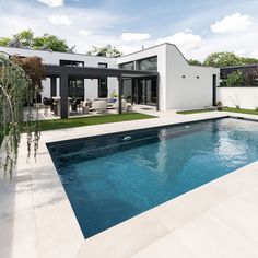 an empty swimming pool in front of a modern house