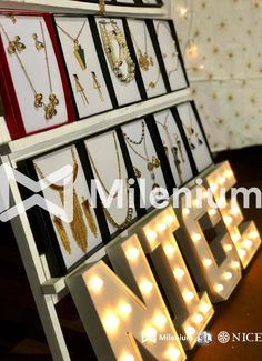 the lighted sign is next to many necklaces on display in front of a wall