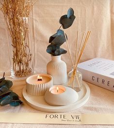 a table topped with candles and vases filled with plants next to a box of cereal