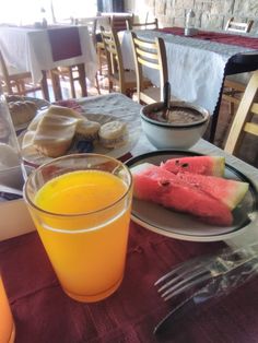 there is a plate with watermelon slices on it and a glass of orange juice